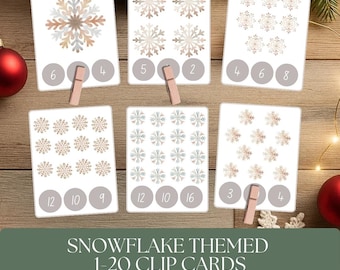 May include: Six white cards with snowflake designs and numbers 1-20. Each card has a different number of snowflakes and corresponding numbers. The text "SNOWFLAKE THEMED 1-20 CLIP CARDS" is at the bottom. Includes clothespins.