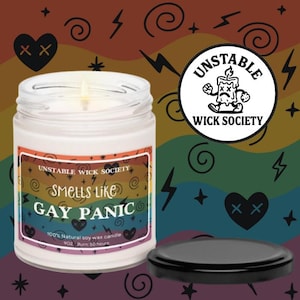 May include: A white glass jar candle with a black lid. The label reads "Smells Like Gay Panic" with a rainbow design. The candle is from Unstable Wick Society. The background features a rainbow pattern, hearts, and lightning bolts.
