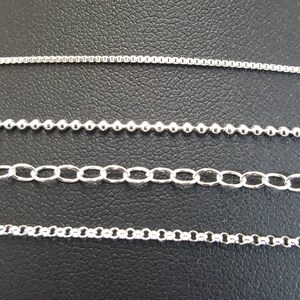 May include: Four different types of silver chains on a black background. The chains are arranged in rows from top to bottom. The top chain is a thin, delicate chain. The second chain is a thicker, more substantial chain. The third chain is a chain with small, round beads. The bottom chain is a chain with larger, oval-shaped links.