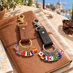 May include: Two leather keychains with metal clasps and rings, one brown and one black, each engraved with the name Ethan. The brown keychain features gold-tone flag charms, while the black keychain features silver-tone flag charms representing various nations.