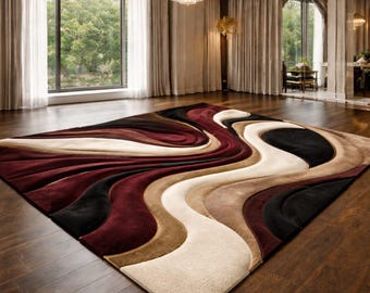 May include: A large, rectangular area rug with a flowing, abstract design. The rug features a mix of colors including burgundy, black, beige, and brown. The rug is placed on a dark wood floor in a well-lit room.