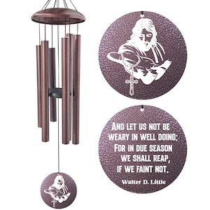 May include: Bronze-colored wind chimes with a circular pendant featuring a white image of Jesus holding a rosary and cross. The bottom pendant has an inspirational quote by Walter D. Little. The chimes have multiple bronze tubes.