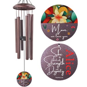 May include: Bronze-colored wind chimes with a floral design and the text "Mom, we love you" and "She is clothed with Strength and Dignity". The wind chimes have a round top and bottom with a floral design.