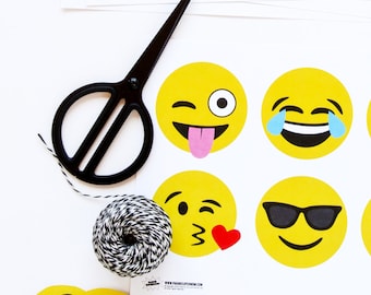 May include: A set of printable emoji party decorations featuring yellow circle stickers with different facial expressions, including winking, tongue sticking out, crying, sunglasses, and blowing a kiss. The stickers are printed on white paper and are ready to be cut out and used for a party.