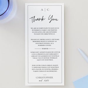 May include: A white wedding thank you card with black text. The card reads "Thank You" in cursive, followed by a message to guests. The card is framed with a thin black border and includes the names "Christopher and Amy".