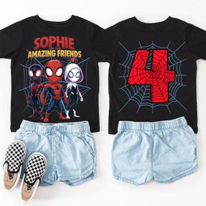 Puede incluir: Dos camisetas negras con gr&aacute;ficos de Spider-Man, pantalones cortos de mezclilla azul claro y zapatos sin cordones a cuadros. Una camiseta dice "Sophie and Her Amazing Friends" con personajes de Spider-Man. La otra camiseta tiene un n&uacute;mero 4 rojo con un dise&ntilde;o de telara&ntilde;a.