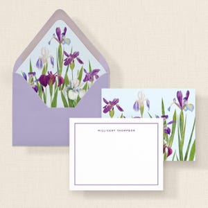 May include: A stationery set featuring a lavender envelope, a matching card, and a blank notecard. The envelope and card have a watercolor design of purple and white irises. The notecard has a purple border and the name "MILLICENT THOMPSON" printed in the upper right corner.