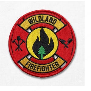 May include: Embroidered patch with a red circular background. The patch features the words "WILDLAND" and "FIREFIGHTER" in yellow, and a central design of a black flame over a green tree. Firefighting tools are on the sides.