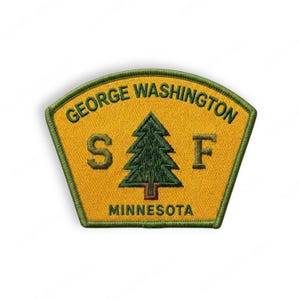 May include: A yellow and green embroidered patch with the text "GEORGE WASHINGTON" above a green pine tree and the letters "S F". The word "MINNESOTA" is below the tree. The patch has a green border.
