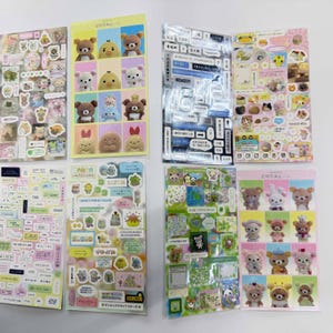 May include: Eight sheets of decorative stickers featuring various cartoon characters, including brown bears, white bears, and yellow chicks. The sheets display a mix of grid-style character portraits, small food items, speech bubbles, and Japanese text.
