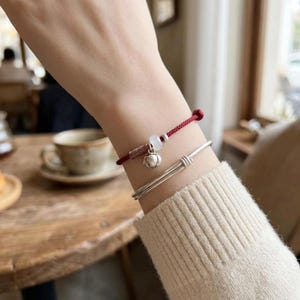 Pulsera con dije de caqui de plata fina 999 y cordón trenzado para la buena suerte.