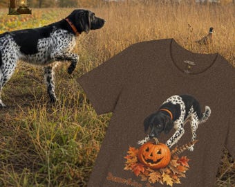 May include: A brown heather t-shirt featuring a graphic of a black and white spotted dog with an orange collar standing over a carved jack-o'-lantern pumpkin surrounded by autumn leaves, with the text "Something smells Spooky" printed below.