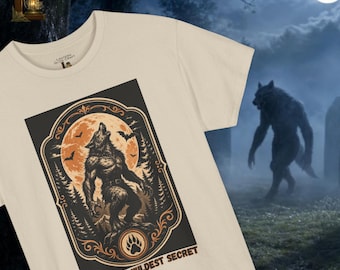 May include: A cream-coloured t-shirt featuring a rectangular graphic of a werewolf howling at a large orange moon. The design includes silhouettes of bats and pine trees within an ornate border, with the text OCTOBER'S WILDEST SECRET below.