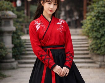 May include: A red and black traditional Chinese Hanfu dress. The red top features white crane embroidery and black trim. The long black skirt is paired with a red sash. The sleeves have black ribbon detailing.