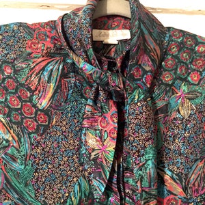 May include: A black silk blouse with a tie neck and a colorful abstract print featuring shades of red, green, blue, and gold.