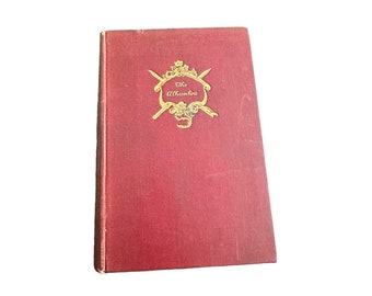 May include: A red hardcover book with the title "The Alhambra" in gold lettering on the front cover. The title is surrounded by a decorative gold design.