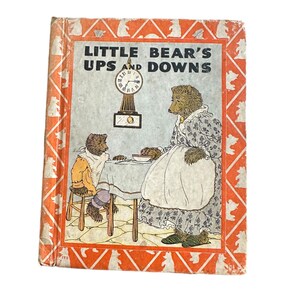 May include: A vintage children's book cover with an illustration of two bears. The book is titled "Little Bear's Ups and Downs". The cover features a red, white, and orange patterned border.