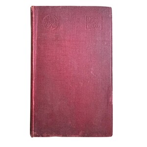May include: A vintage book with a textured, burgundy cover. The cover features a circular emblem and the text "Tom University Library" in a rectangular box. The book's edges show signs of wear.
