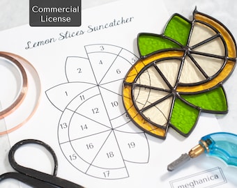 May include: A stained glass suncatcher shaped like lemon slices with yellow and green glass segments joined by dark solder lines. Beside it lies a printed pattern sheet labeled Lemon Slices Suncatcher, copper foil tape, black scissors, and a blue glass cutter tool.