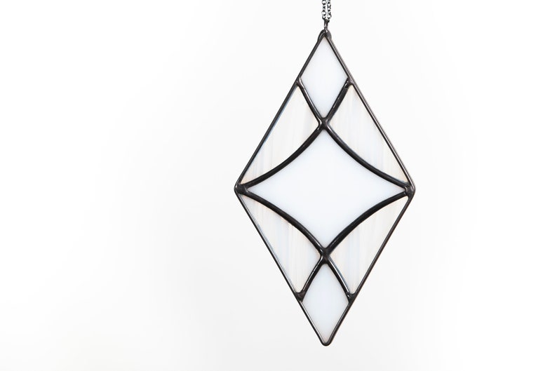 Curved design stained glass suncatcher made with opaque white and wispy white and clear glass. Made in the Tiffany Glass style and with black patina. Hangs on a black chain on a white background to show color and texture of glass art.