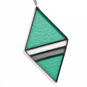 Geometric, modern stained glass suncatcher made with green, grey and clear wavy textured glass. Made in the Tiffany Glass style and with black patina. Displayed on a white background to show color and wavy texture of glass art.