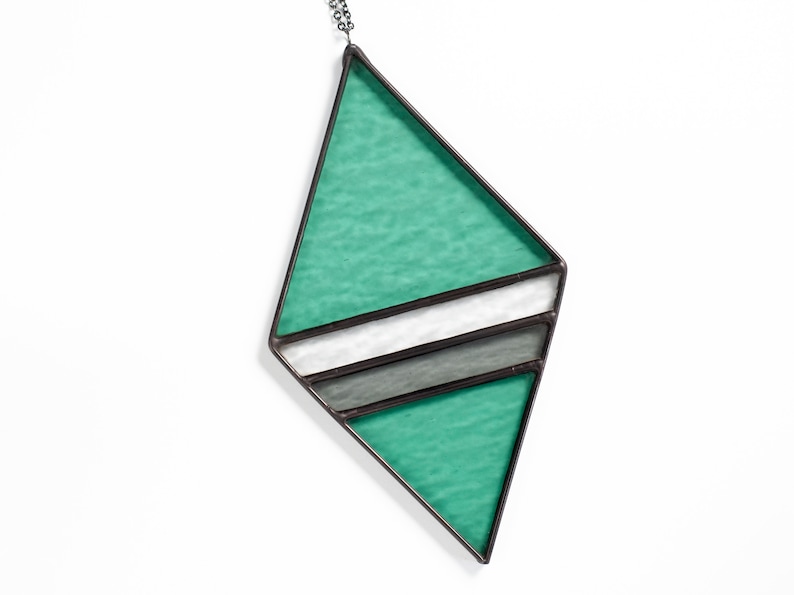 Geometric, modern stained glass suncatcher made with green, grey and clear wavy textured glass. Made in the Tiffany Glass style and with black patina. Displayed on a white background to show color and wavy texture of glass art.