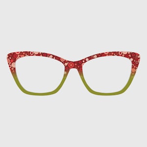 Puede incluir: Gafas de estilo ojo de gato con un patrón de lunares rojos y blancos en las monturas. La parte inferior de las monturas es verde degradado. Las lentes son transparentes.