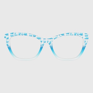 Puede incluir: Gafas de estilo ojo de gato con montura degradada blanca y azul. La montura está decorada con un patrón de formas de nubes azules. Las lentes son transparentes. Las gafas están sobre un fondo gris claro.