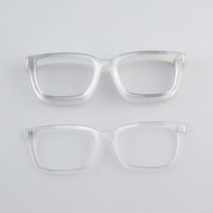 May include: Two pairs of clear, square-framed eyeglasses are displayed against a white background. The glasses have a classic, slightly oversized design, with visible hinges and a transparent appearance. The frames are made of a clear material.
