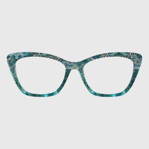 May include: Cat-eye spectacles with a teal and blue patterned design. The frames feature a repeating pattern of abstract shapes and figures. The lenses are clear, and the overall aesthetic is modern and stylish.