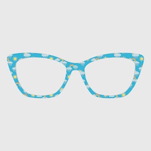 Puede incluir: Gafas de ojo de gato azules con un patrón repetido de arcoíris, nubes y soles. Las monturas tienen un fondo azul claro. Un accesorio divertido y caprichoso.