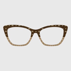 May include: Brown cat-eye eyeglasses with a patterned design. The upper portion of the frames features a dark brown color with small white floral and bow accents. The lower portion of the frames has a tan and white checkered pattern.
