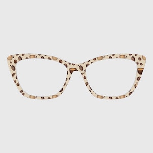 May include: Cat-eye style eyeglasses with a beige background, patterned with coffee beans and coffee cups in shades of brown. The glasses have a classic, retro design.