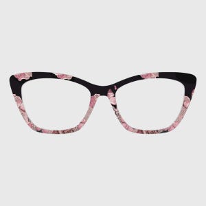 Könnte beinhalten: Schwarze Cat-Eye-Brille mit einem rosa und weißen Blumenmuster. Die Fassungen haben eine glänzende Oberfläche und eine klassische Form. Die Gläser sind klar.