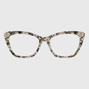 May include: Cat-eye spectacles with a floral design. The frames have a black base decorated with white and gold flowers. The lenses are clear, and the overall design is stylish and feminine.