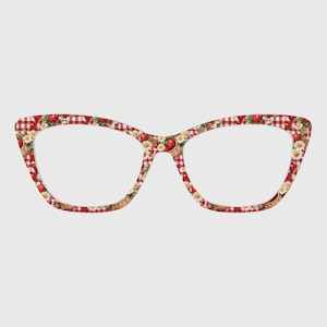 May include: Cat-eye glasses frames featuring a red and white gingham pattern overlaid with a print of small woven baskets filled with red strawberries and white daisy flowers. The frames have a distinct pointed shape at the outer top corners.