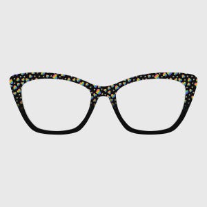 Puede incluir: Gafas de estilo ojo de gato con montura negra y un patrón de corazones coloridos. Las lentes son transparentes y la montura tiene una forma sutil y elegante. El patrón de corazones incluye un arcoíris de colores.