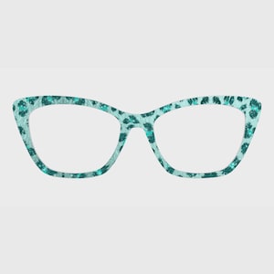 May include: Teal cat-eye glasses featuring a leopard print design. The frames have a light teal base with darker teal spots and glitter details. The lenses are clear. The glasses have a fashionable, contemporary design.