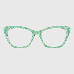 Può includere: Occhiali da vista stile cat-eye con un motivo marmorizzato nei toni del verde acqua e dell'oro. Le montature hanno una forma classica con un angolo superiore leggermente appuntito. Le lenti sono trasparenti.