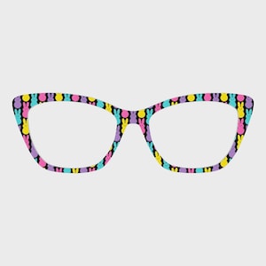 Könnte beinhalten: Brille im Cat-Eye-Stil mit einem schwarzen Rahmen, der mit einem sich wiederholenden Muster aus bunten Osterhasen-Formen verziert ist. Die Hasen sind gelb, rosa, lila und blau. Die Gläser sind klar.