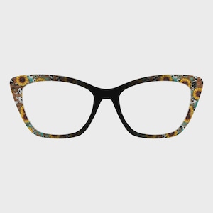May include: Cat-eye style eyeglasses with a black frame and a decorative pattern. The pattern features sunflowers, turquoise, and a cowhide print. The lenses are clear. The glasses are designed for vision correction or fashion.