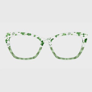 May include: Cat-eye glasses frames featuring a two-tone design. The upper portion of the frames displays a white background with a green watercolor shamrock pattern, while the lower portion features a light and dark green checkered gingham print.