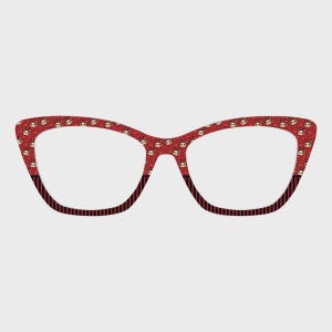 May include: Red cat-eye eyeglasses with a repeating pattern of small faces. The frames have a black and red striped design at the bottom. The glasses are set against a plain white background.