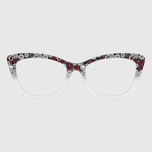 May include: Cat-eye style eyeglasses with a floral pattern of red roses, gray roses, and skulls on a black background. The frames fade to white near the lenses.