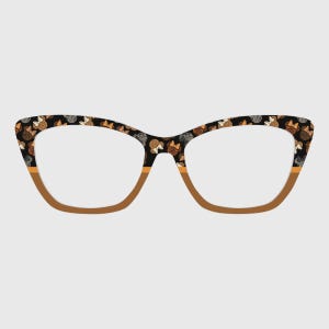 Puede incluir: Gafas de estilo ojo de gato con montura negra estampada con pequeñas ilustraciones repetidas en tonos marrón, naranja y blanco. La parte inferior de la montura es de color marrón liso. Las lentes son transparentes.