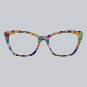 Può includere: Un paio di occhiali con un design colorato e fantasia. Le montature hanno una forma a occhi di gatto e sono decorate con un mosaico di vari colori, tra cui rosso, blu, verde e giallo, su uno sfondo grigio.