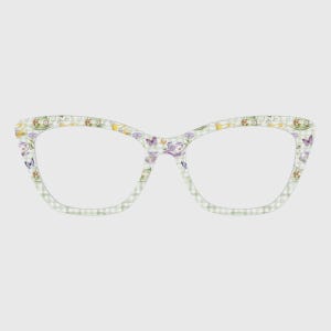 May include: Cat-eye style eyeglasses with a light green and white checkered pattern. The frames are decorated with floral and butterfly designs in shades of purple, yellow, and green. The lenses are clear.