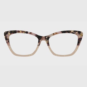 Könnte beinhalten: Katzenaugen-Brille mit zweifarbigem Rahmendesign. Der obere Teil des Rahmens zeigt ein dunkelviolettes und schwarzes Marmormuster mit goldenen Sprenkeln, während der untere Teil in einem durchscheinenden hellen Beige- oder Nudeton gehalten ist.