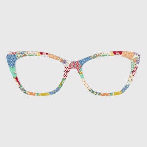 May include: Cat-eye glasses frames featuring a multi-colored patchwork pattern. The design includes various small floral, geometric, and polka dot prints in shades of red, blue, yellow, green, and white across the entire frame surface.