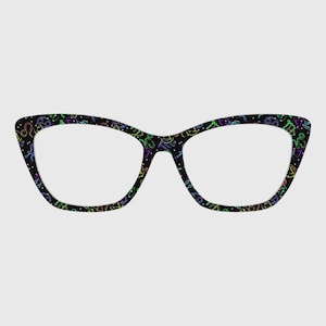 May include: Black cat-eye glasses with a colorful zodiac pattern. The frames feature a repeating design of astrological symbols in neon green, blue, purple, and yellow. The glasses have a classic, retro shape.